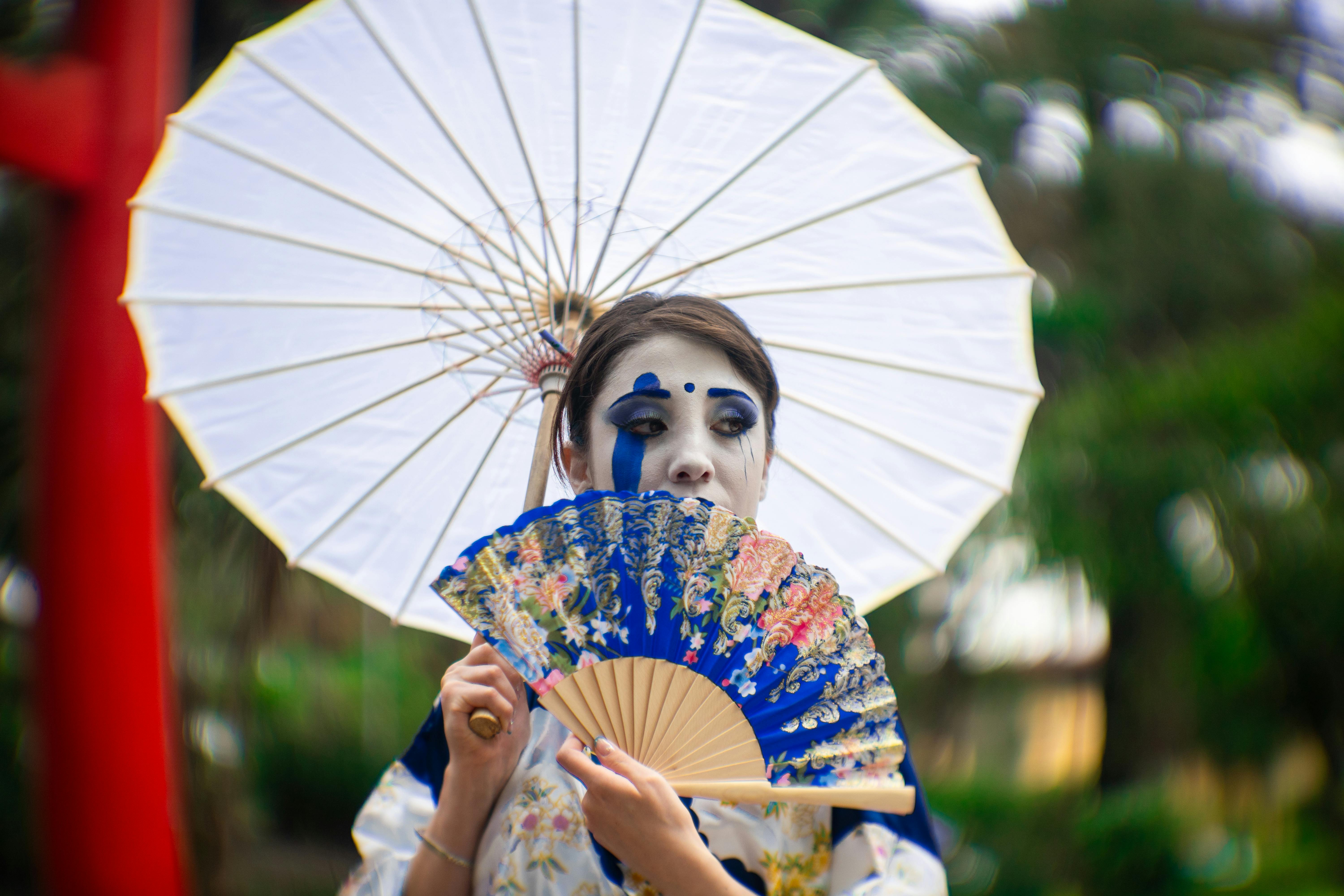 Woman in Japanese-inspired makeup and kimono with umbrella in Mexico City park.