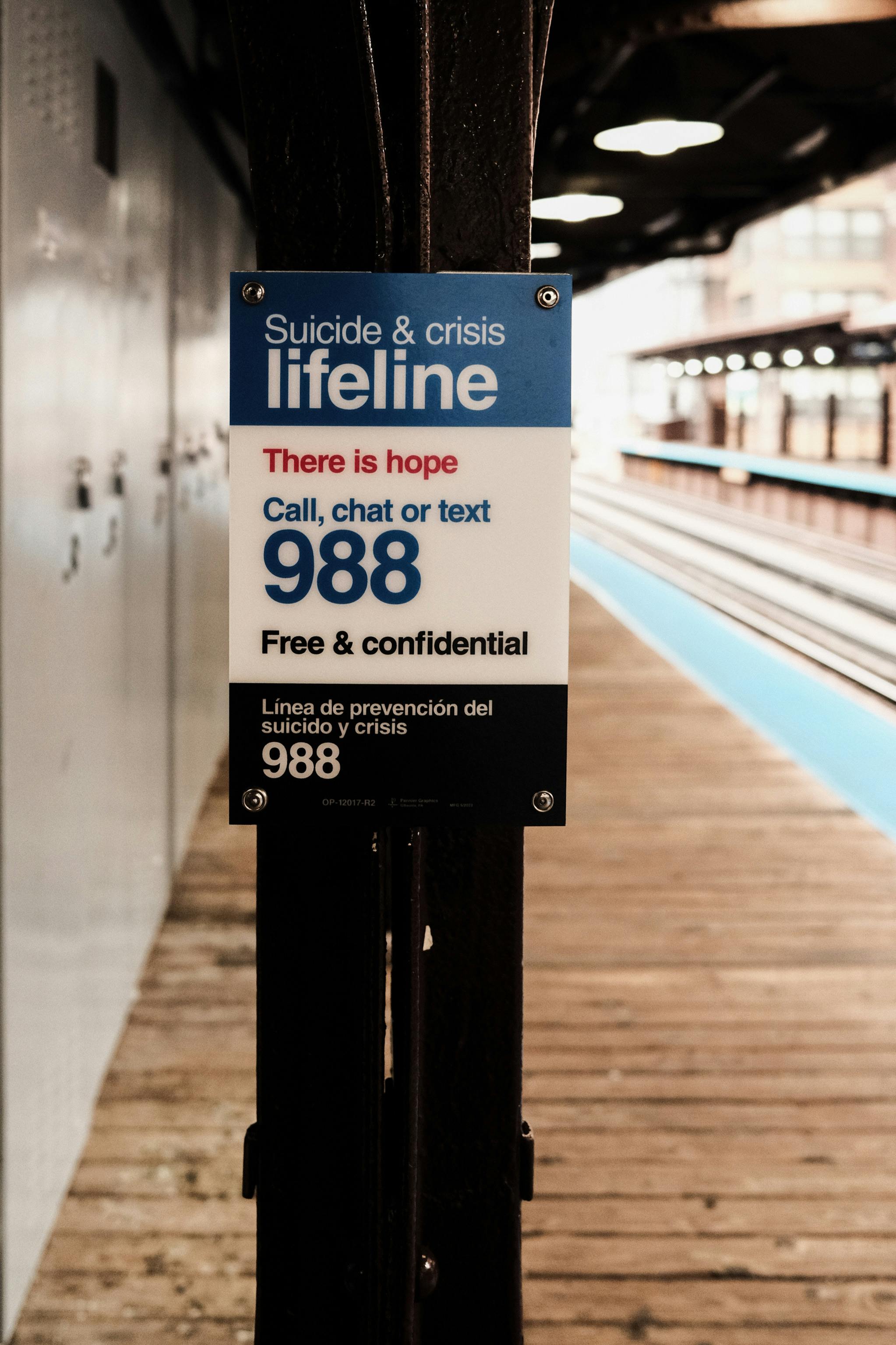 A sign for suicide and crisis support on a train platform, offering free and confidential help.