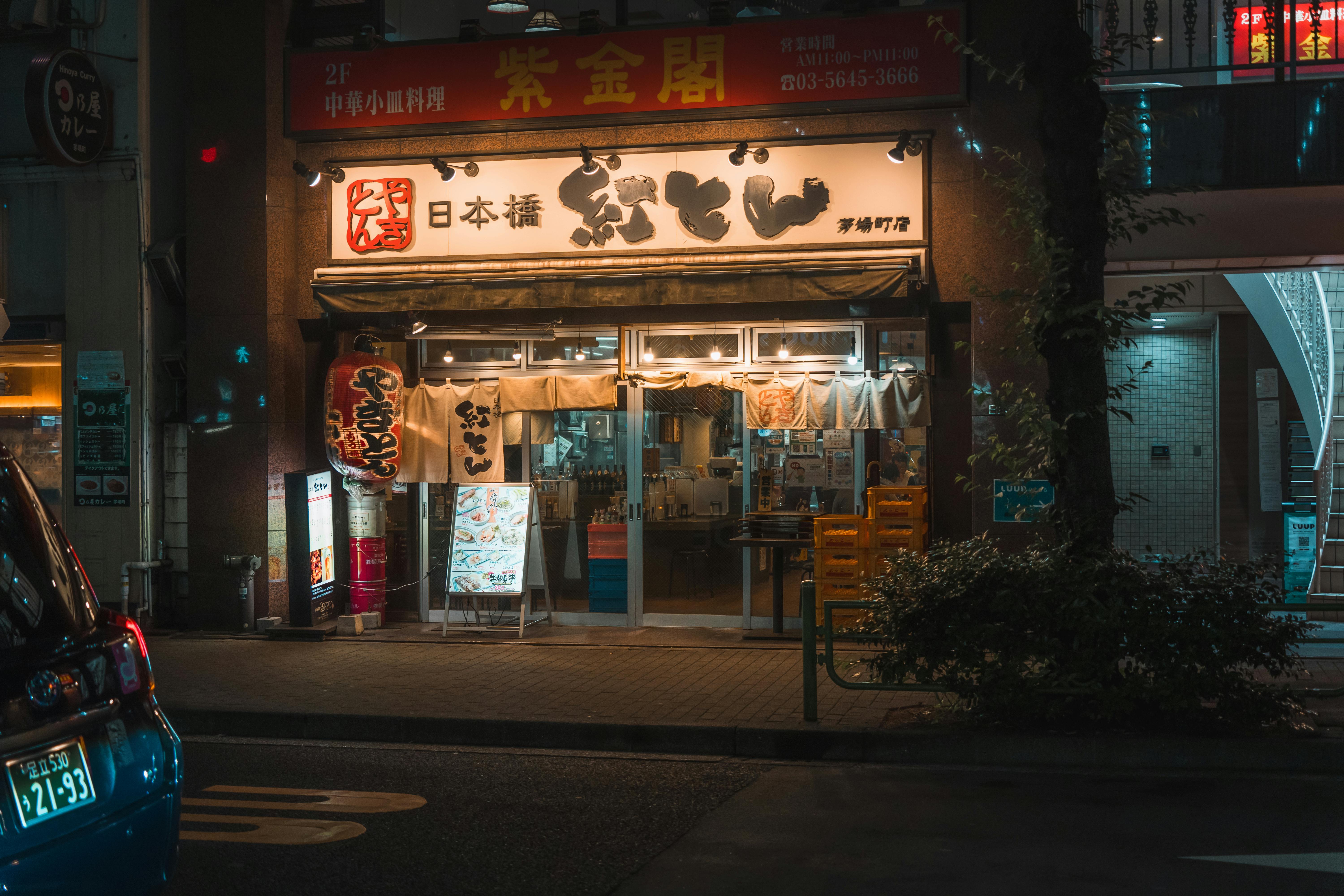 A warmly lit Japanese restaurant in Tokyo captured at night with distinct Japanese signage.