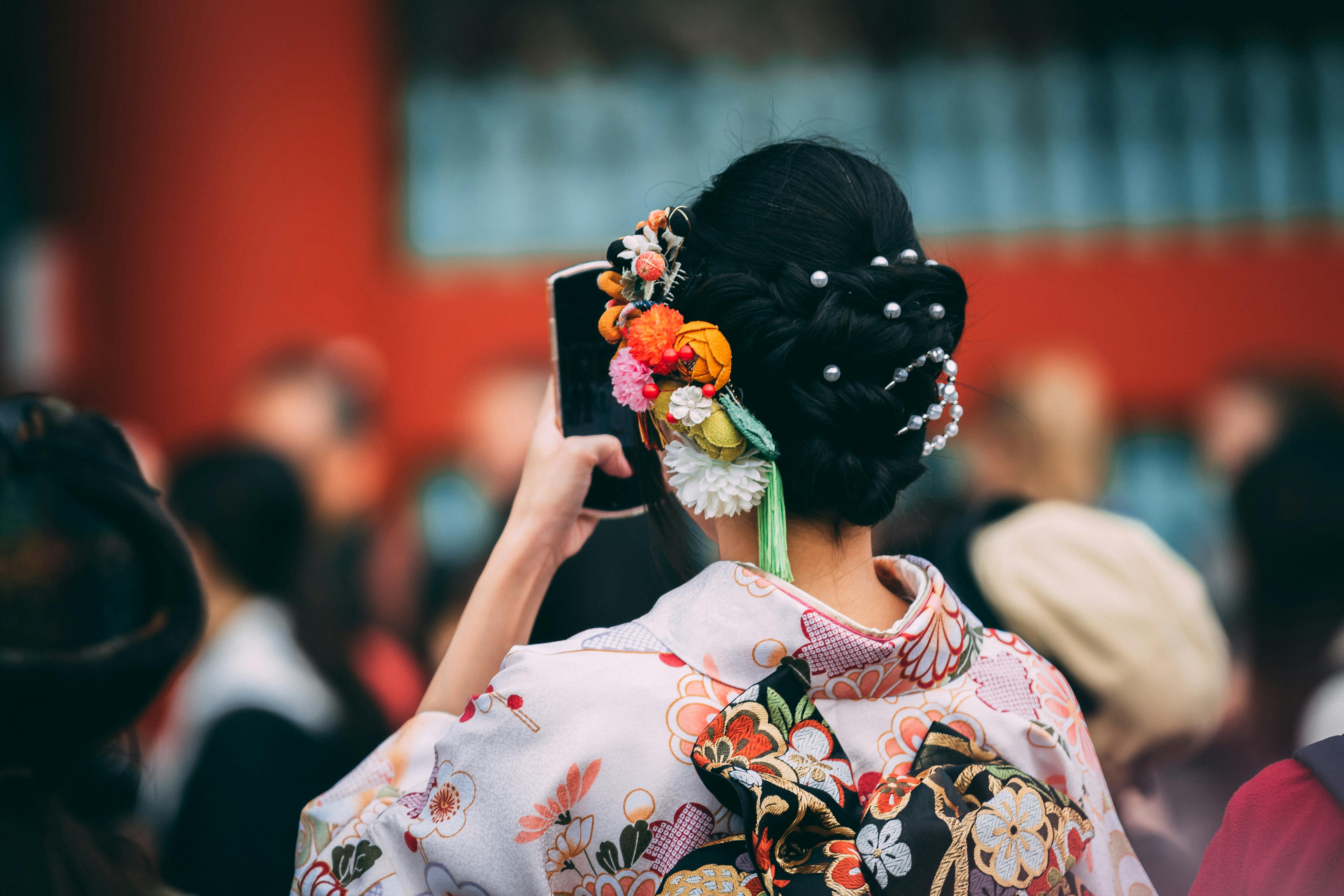 Rear view of woman in a kimono with floral hair accessories at a Japanese festival.