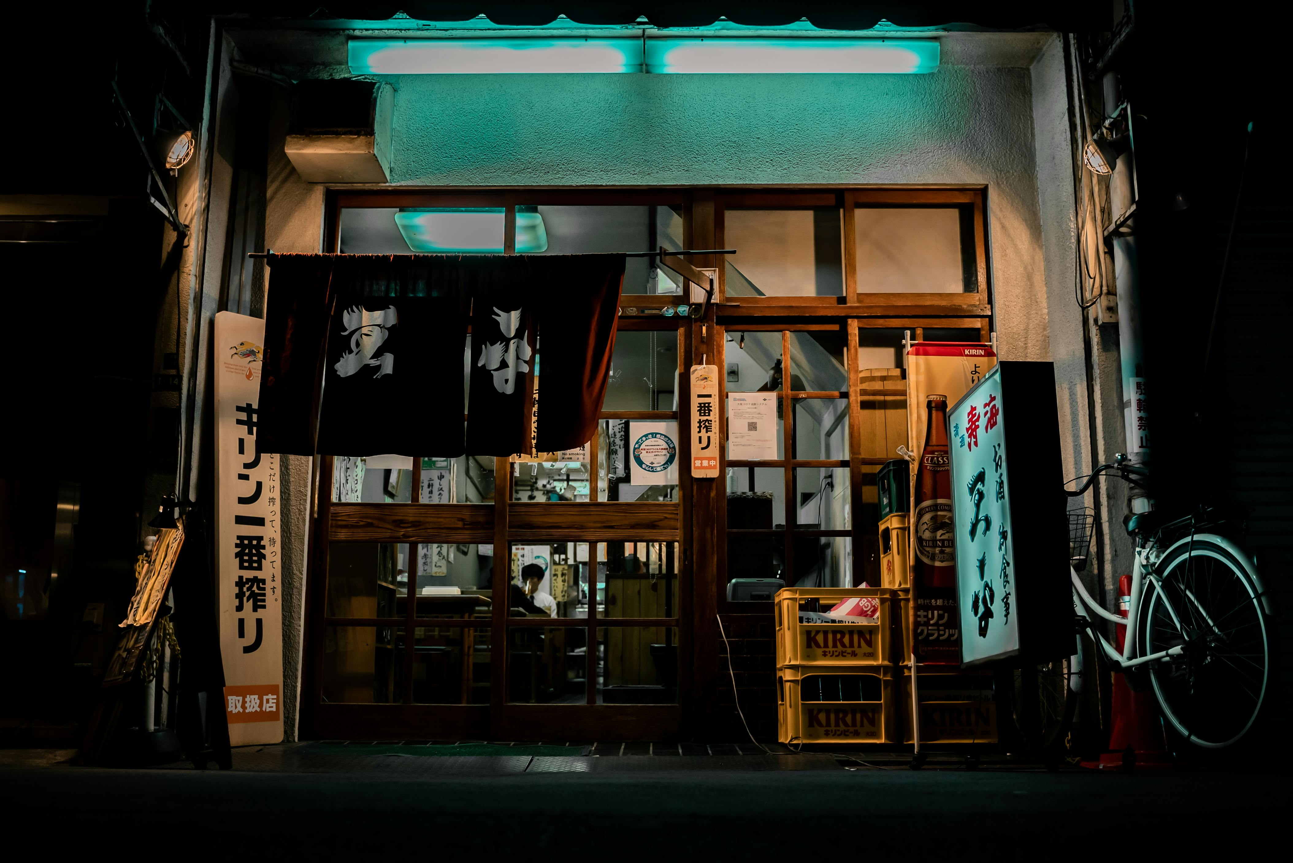 A neon-lit traditional izakaya facade in Osaka, showcasing Japanese cultural elements and vibrant street life.