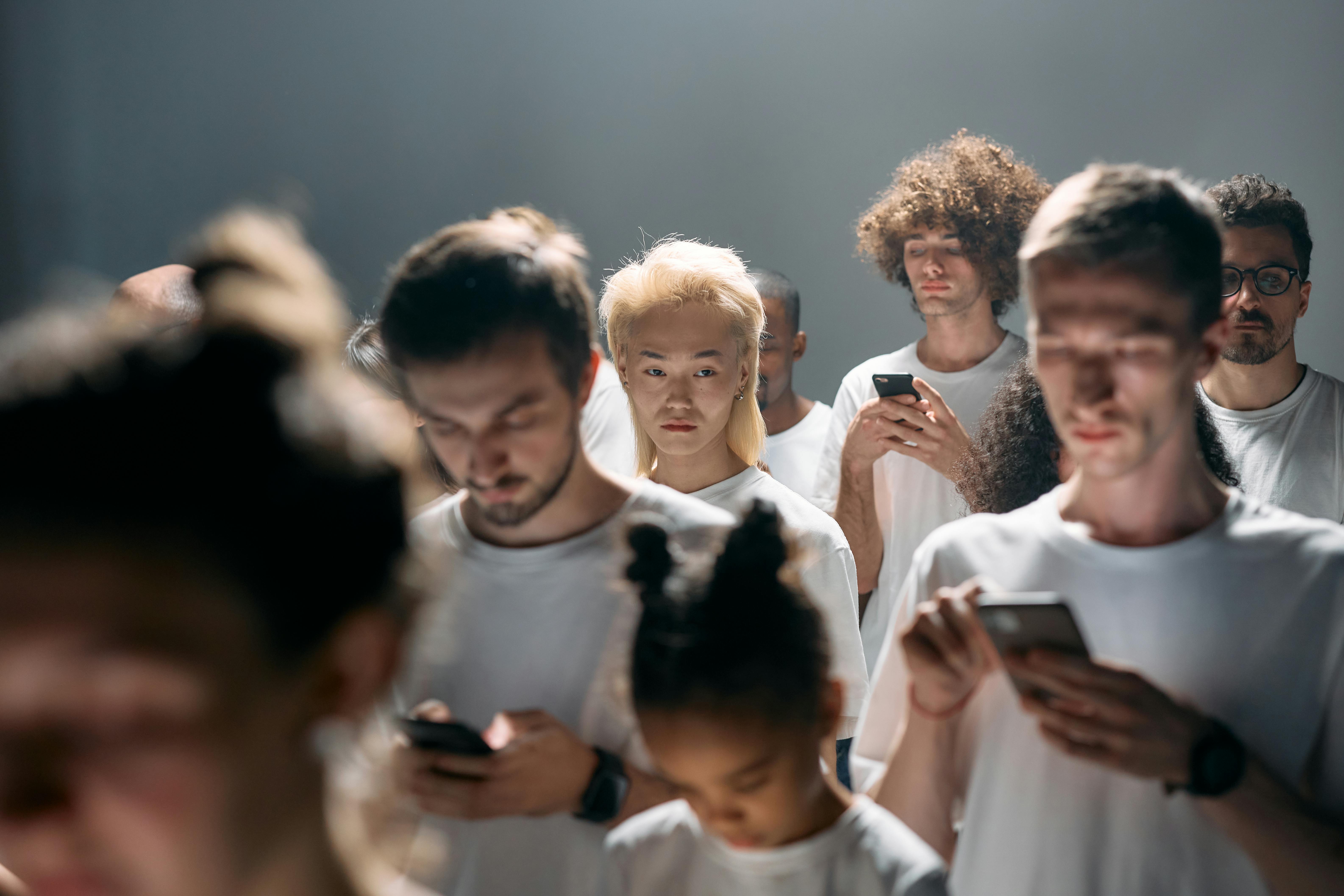 A diverse group of people looking at smartphones, illustrating social isolation in modern technology.