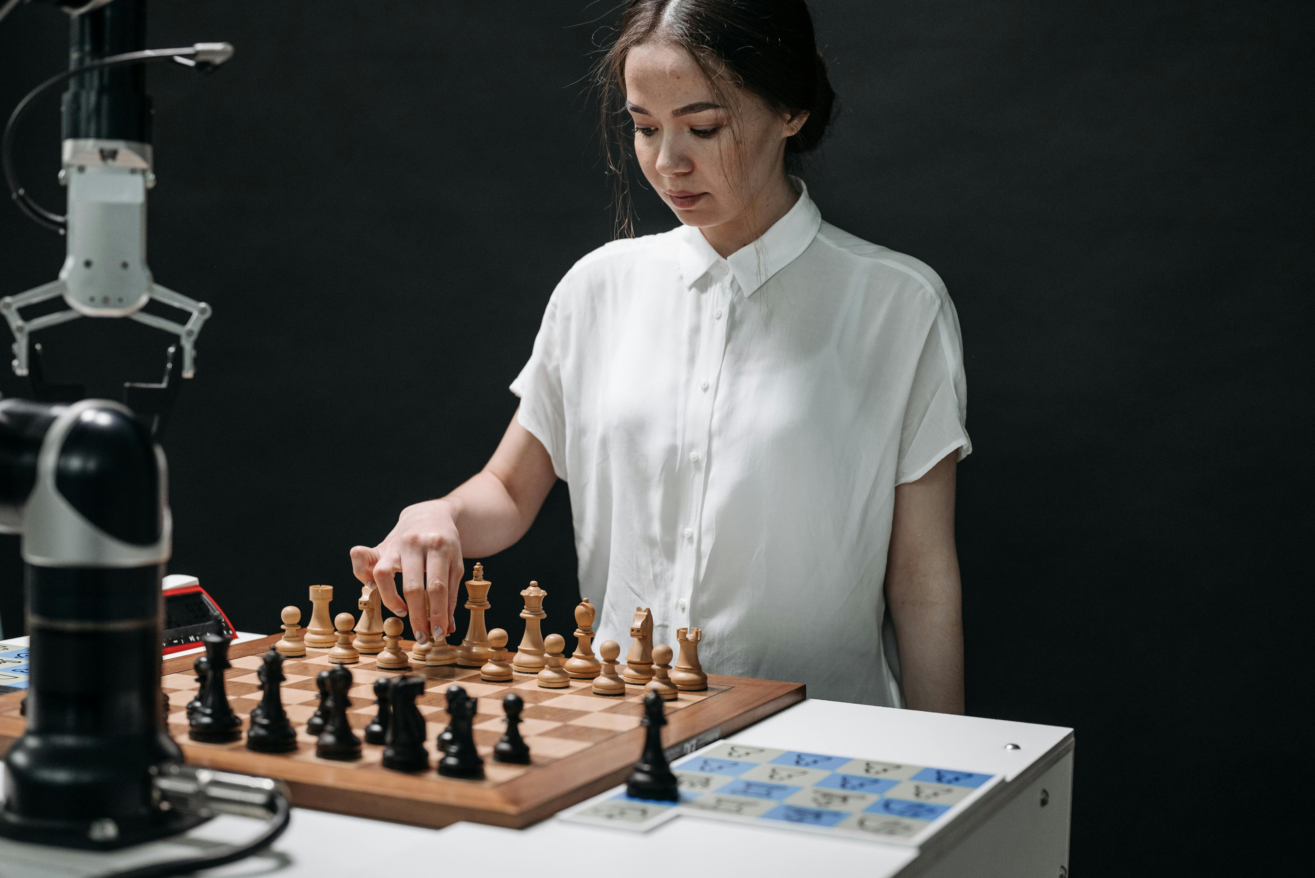 A woman plays chess with a robotic arm, illustrating technology and strategy in a modern context.