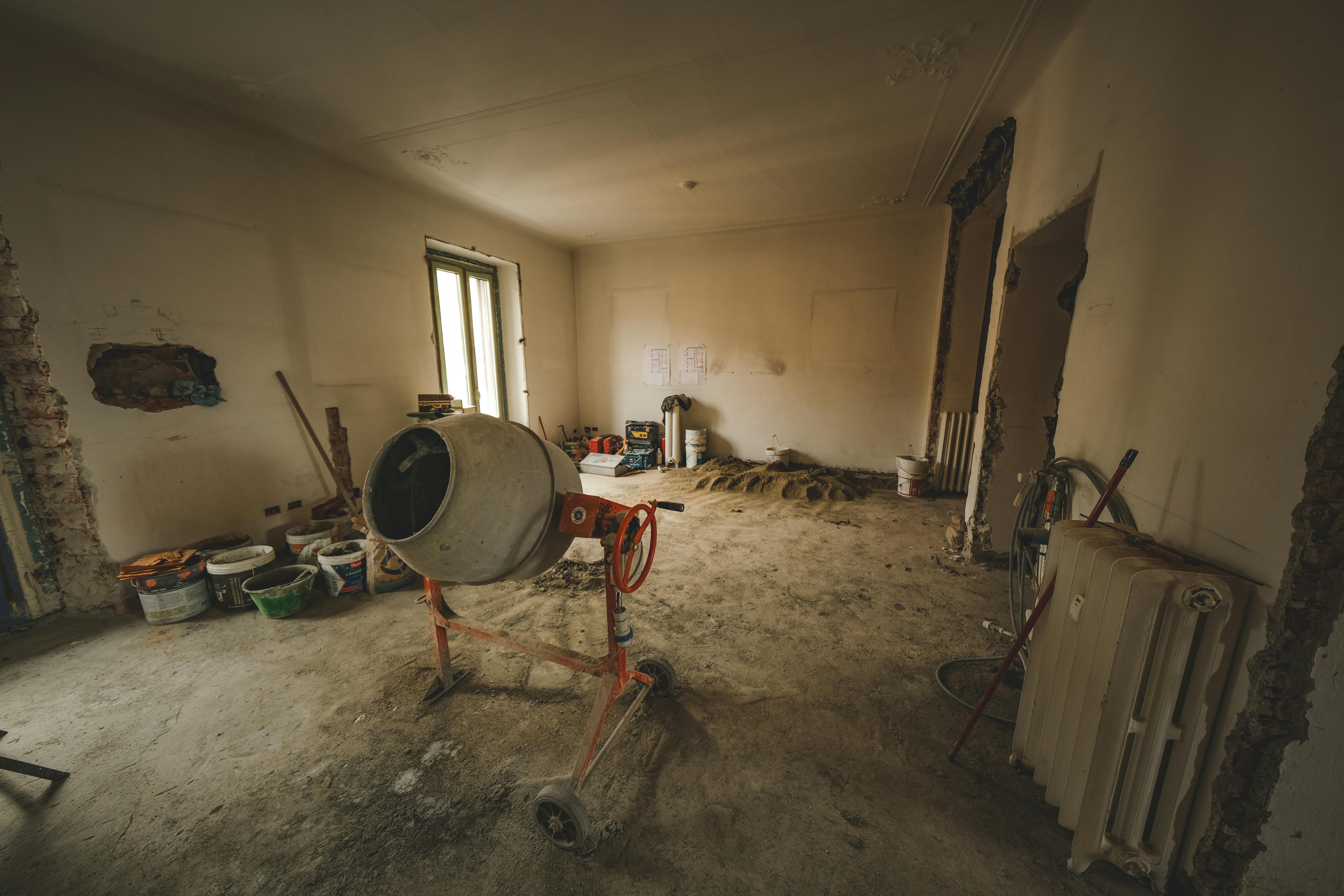 Empty room with a concrete mixer and tools, ideal for renovation concepts.