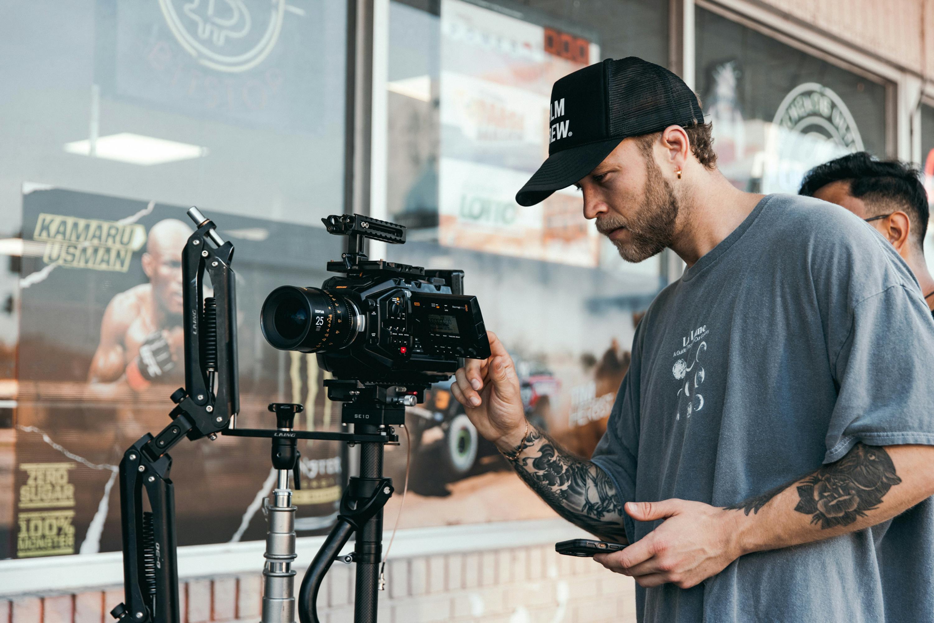 A filmmaker in a casual setting adjusting a professional camera rig for shooting.