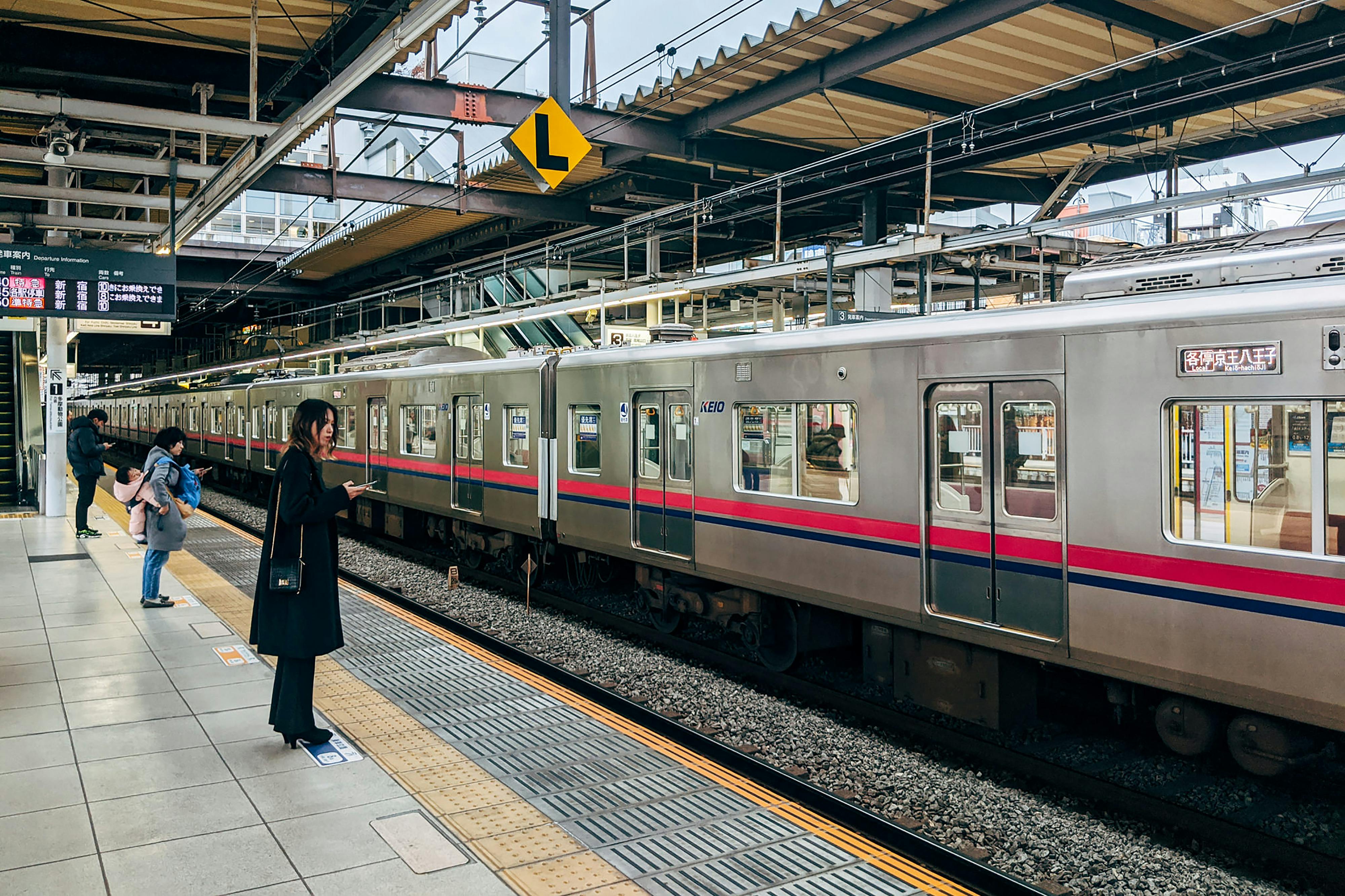 Commuters wait at a Tokyo train station platform, capturing urban life in Japan.