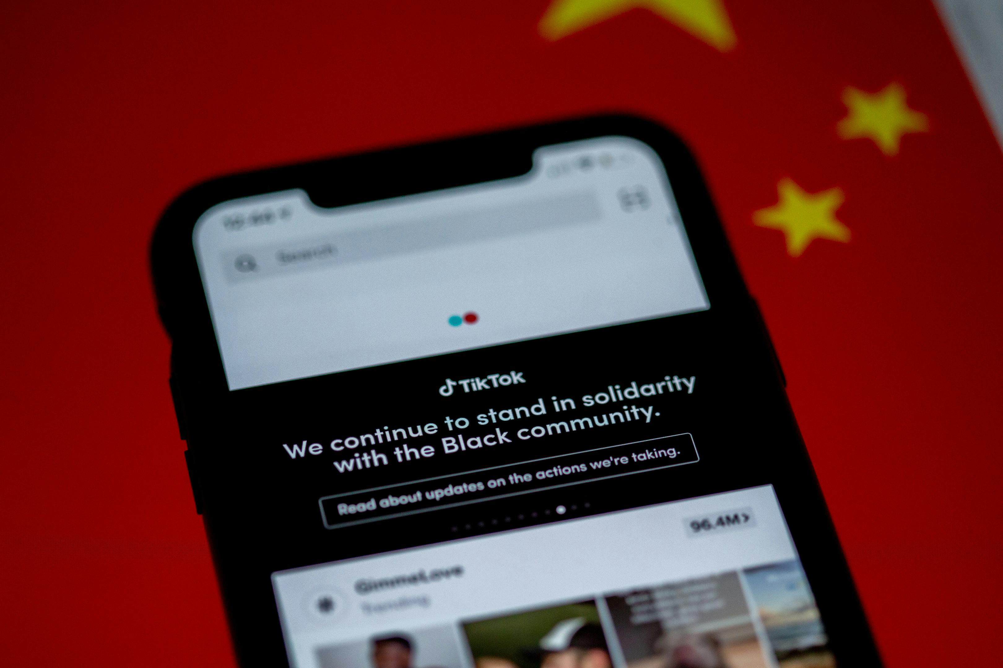 Close-up of a smartphone with TikTok app displayed against a China flag backdrop, highlighting solidarity message.