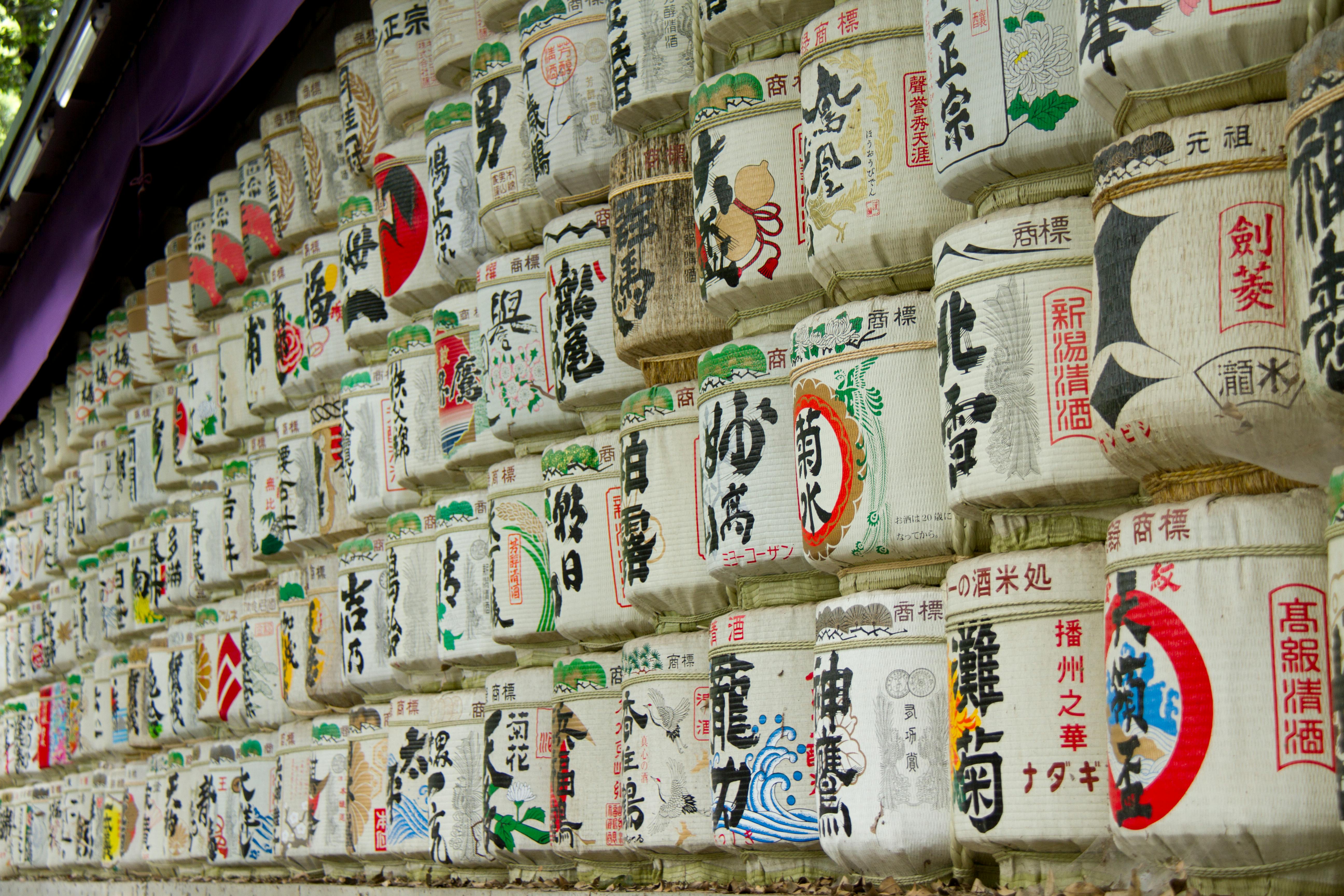 Traditional Japanese sake barrels with vibrant art displayed on shelves in a cultural exhibit.