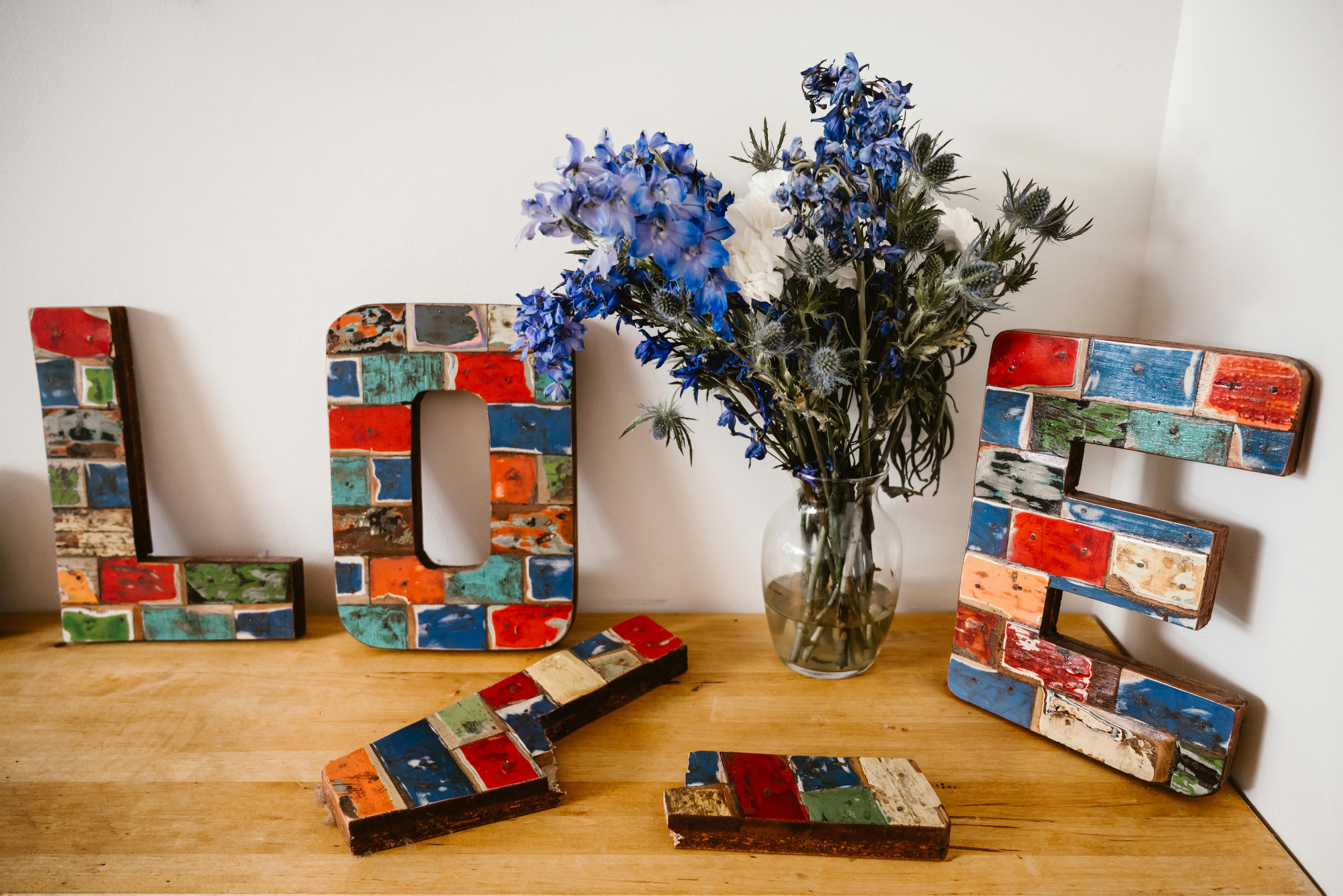 Colorful wooden love letters and vibrant floral bouquet in a rustic setting.