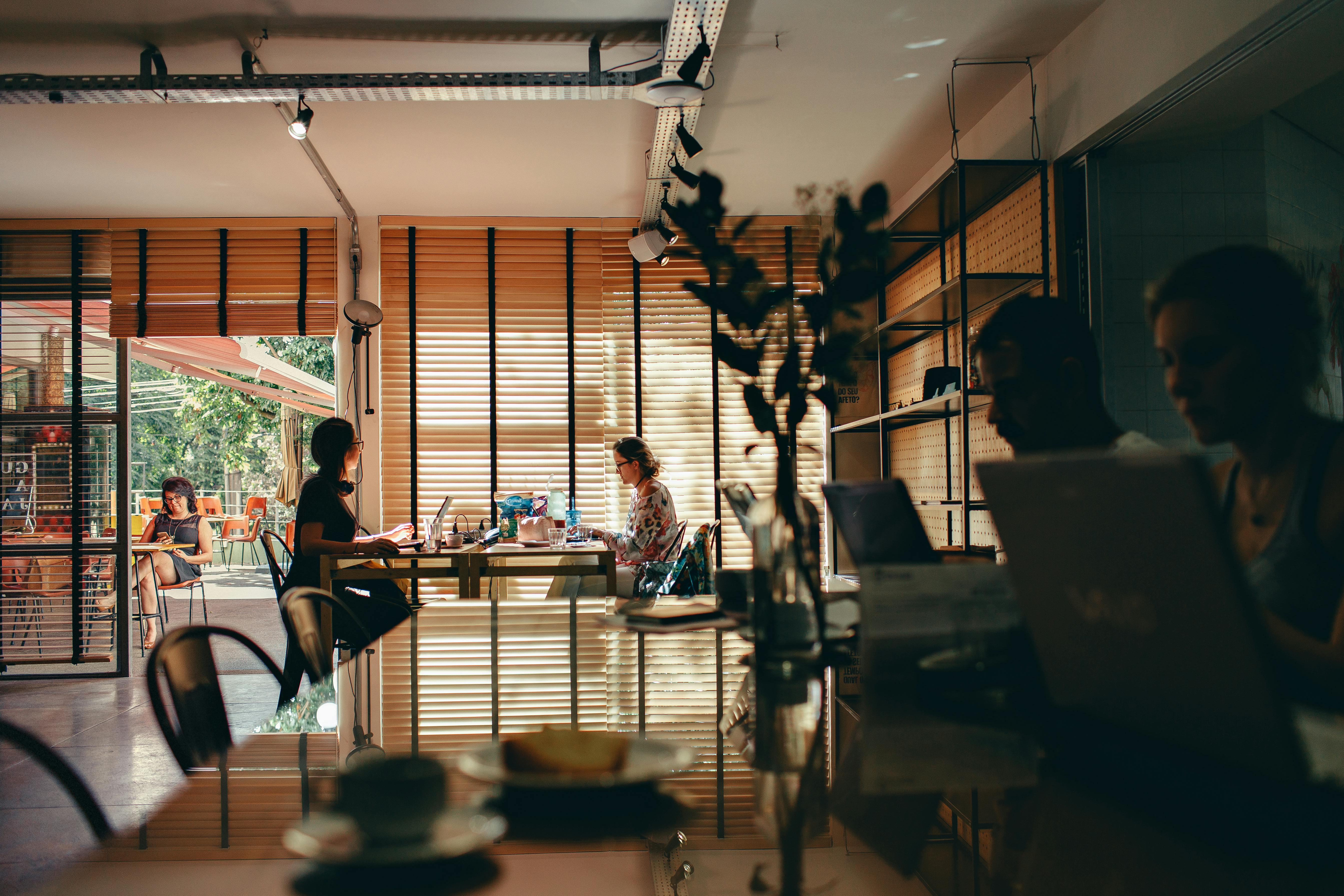 Interior of a bustling café with people working on laptops, creating a modern, collaborative atmosphere.